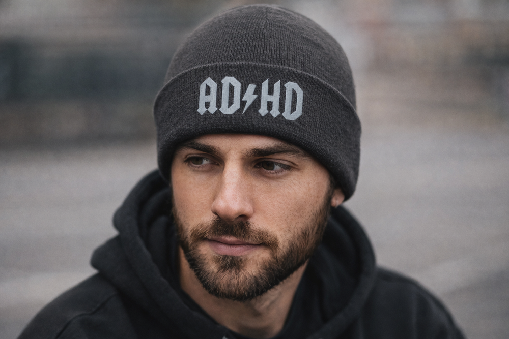 Model wearing a charcoal AD-HD high voltage cuffed beanie with silver lightning bolt embroidery in an urban outdoor setting.
