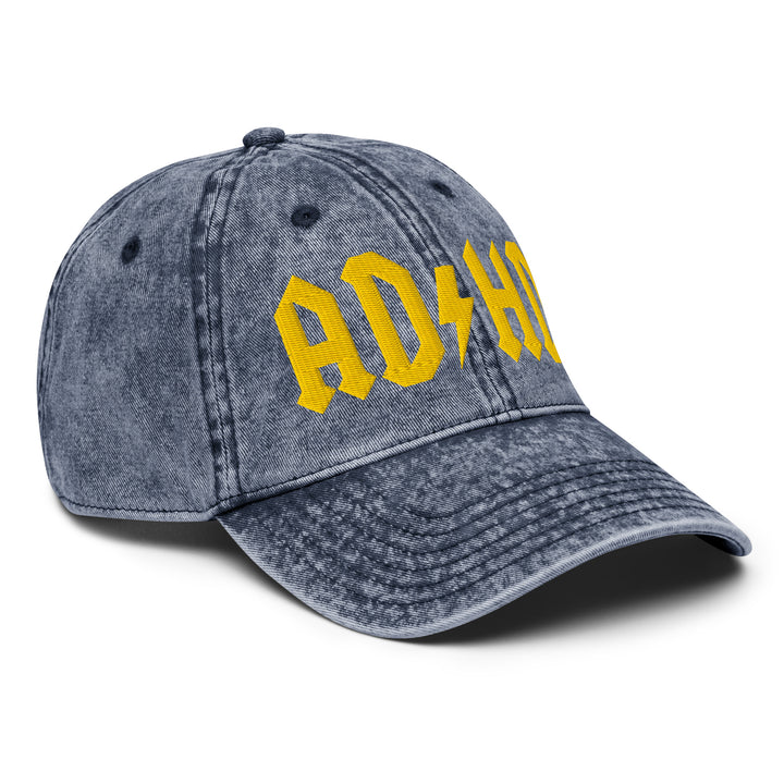 Angled view of a vintage denim dad cap with AD/HD High Voltage embroidered lettering