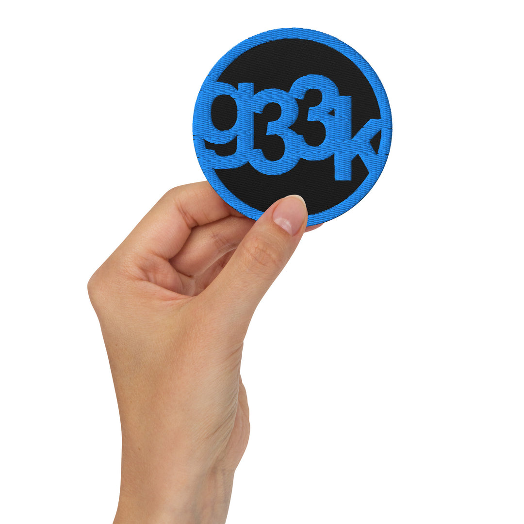 Black circular embroidered g33k leetspeak patch held in hand
