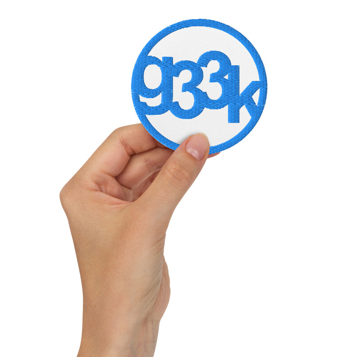 White circular embroidered g33k leetspeak patch held in hand