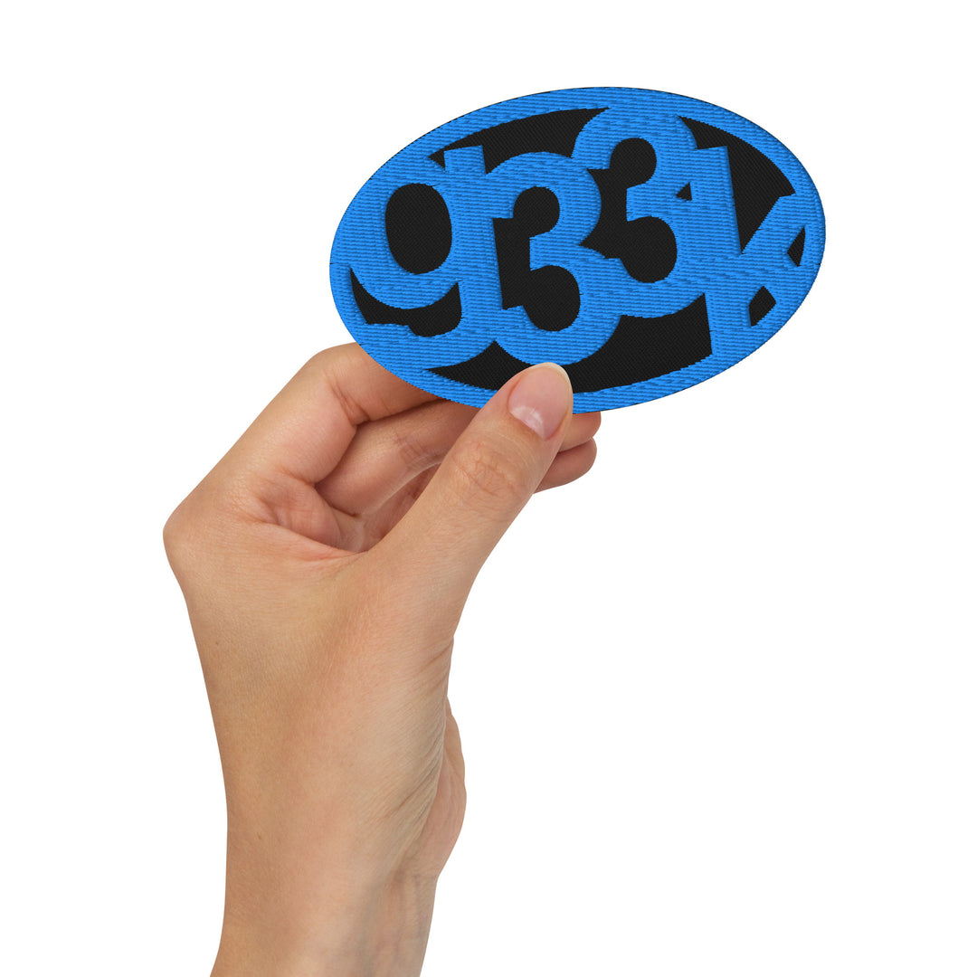 Black oval embroidered g33k leetspeak patch held in hand