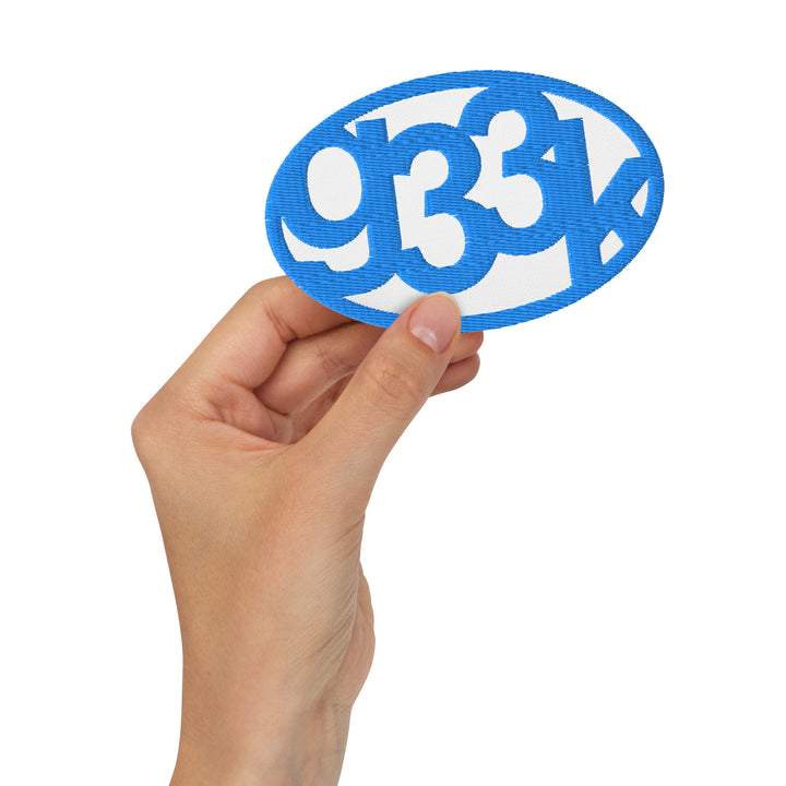 White oval embroidered g33k leetspeak patch held in hand