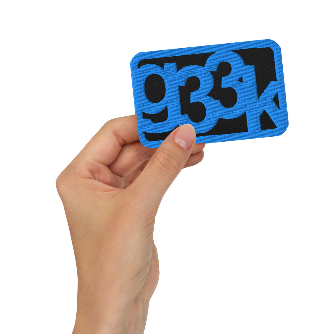 Black rectangular embroidered g33k leetspeak patch held in hand