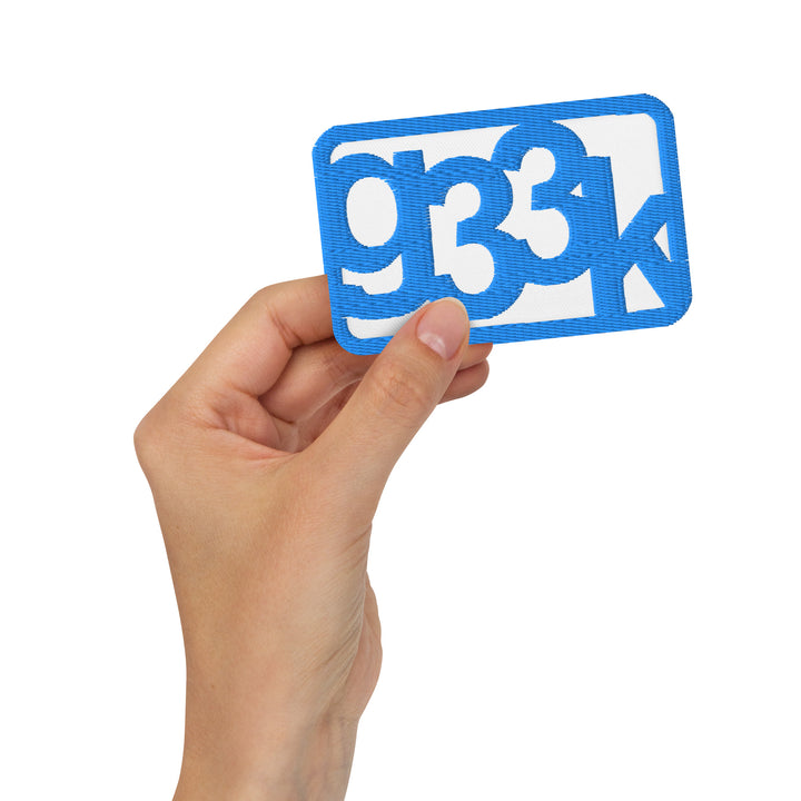 White rectangular embroidered g33k leetspeak patch held in hand