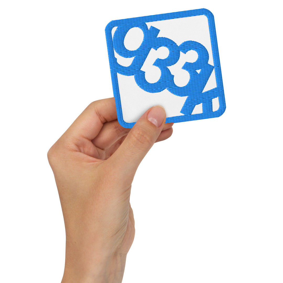 White square embroidered g33k leetspeak patch held in hand