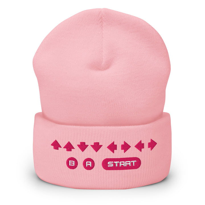 Front view of a pink cuffed beanie with embroidered retro cheat code arrows and B, A, START symbols across the cuff.