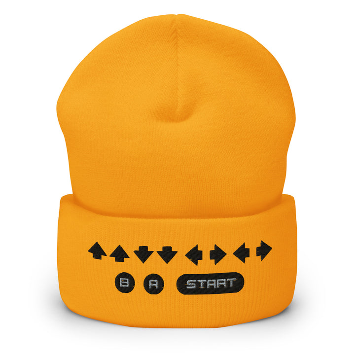 Front view of a yellow cuffed beanie displaying embroidered retro cheat code arrows and classic B, A, START icons on the cuff.