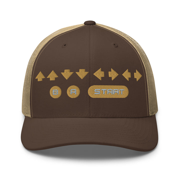 Front view of a brown and khaki snapback trucker cap with gold embroidered retro cheat code arrows and B A START buttons on the front panel