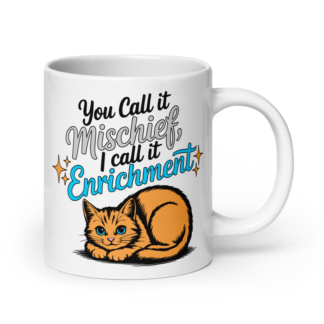 Left side view of the Keep It Geek “You Call It Mischief, I Call It Enrichment” orange cat glossy coffee mug, featuring bold typography with logo-matched blue accents and an illustrated orange cat resting beneath the phrase on a white ceramic mug.