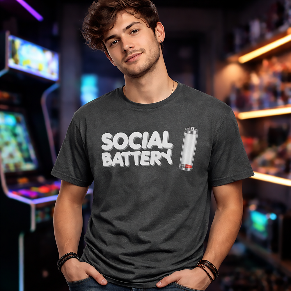 Model wearing a dark heather “Social Battery” t-shirt with a low-charge battery icon—aka the universal symbol for “I’m here, but I’m running on fumes.”