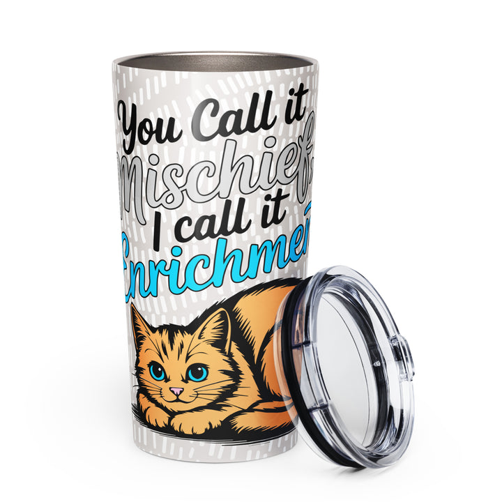 White 20 oz tapered stainless steel tumbler with “You Call it Mischief, I Call it Enrichment” orange cat design, shown from the front with the lid beside it.
